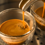 mainstream of strong espresso coffee from a espresso machine to translucent glass cups